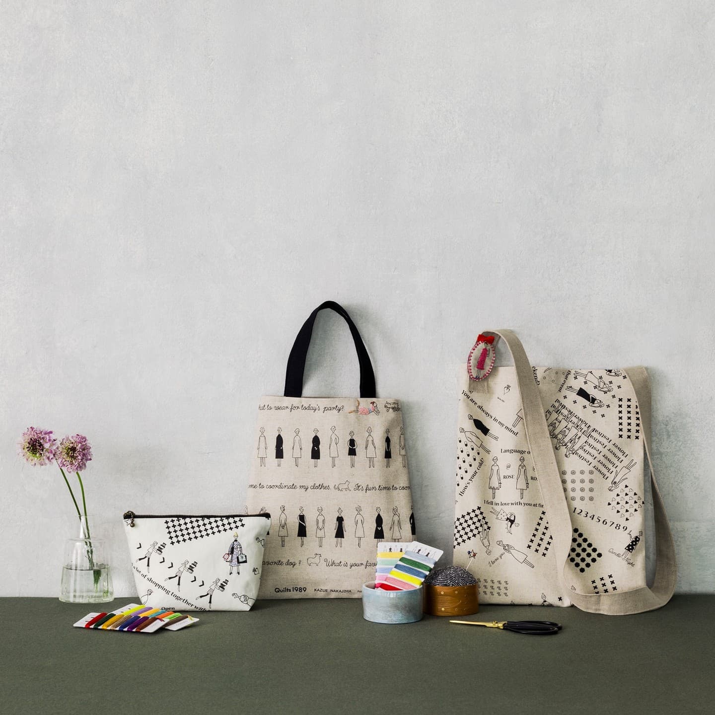 Linen tote bags and a zip pouch with black-line fashion embroidery and small accent stitches