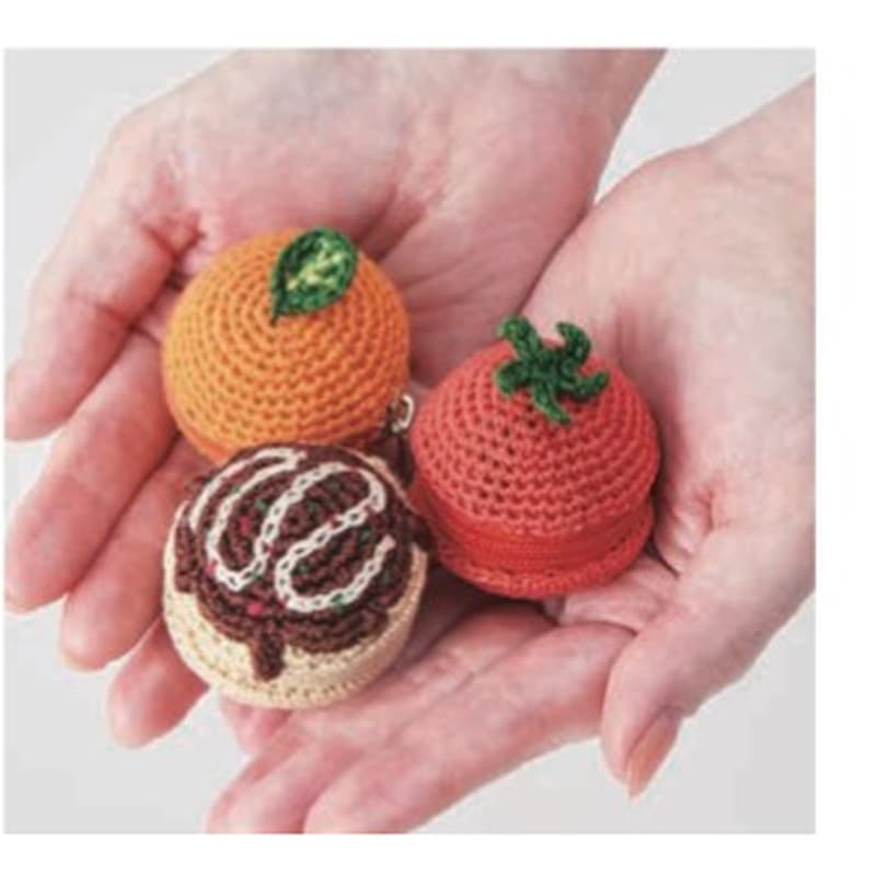 Hands holding small crocheted food pouches with embroidered details