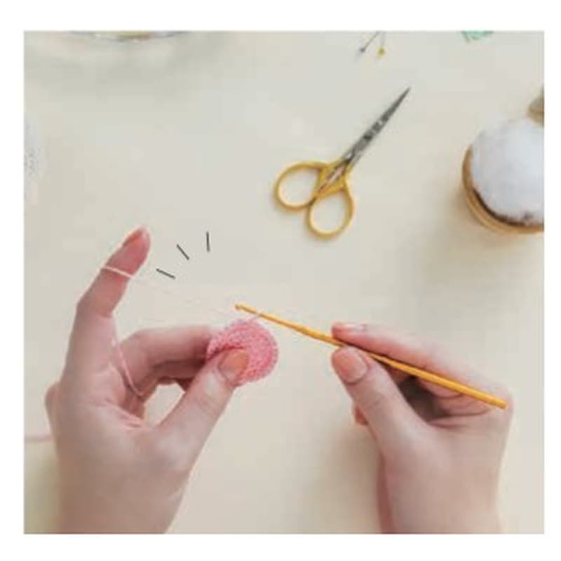 Hands crocheting a small pouch with embroidery floss