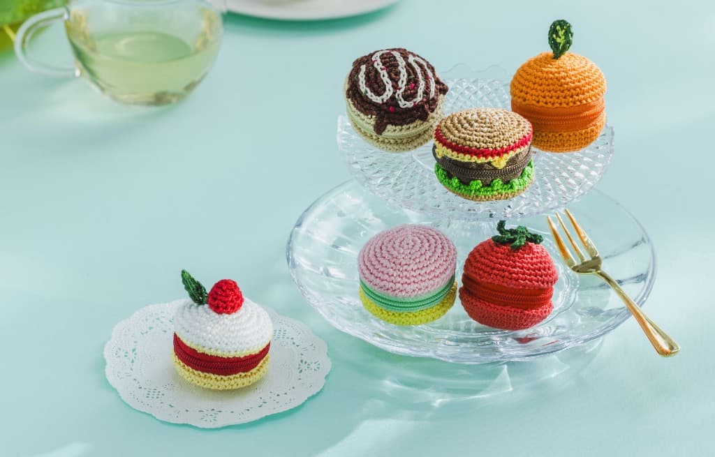 Small food-themed crochet pouches on a glass stand