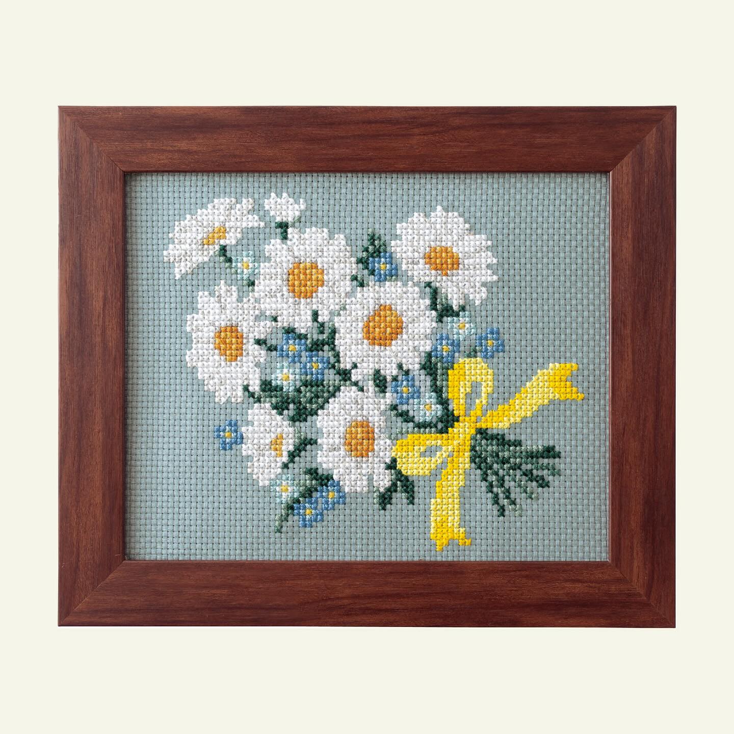 Framed white daisy and blue forget-me-not bouquet on blue-grey cloth