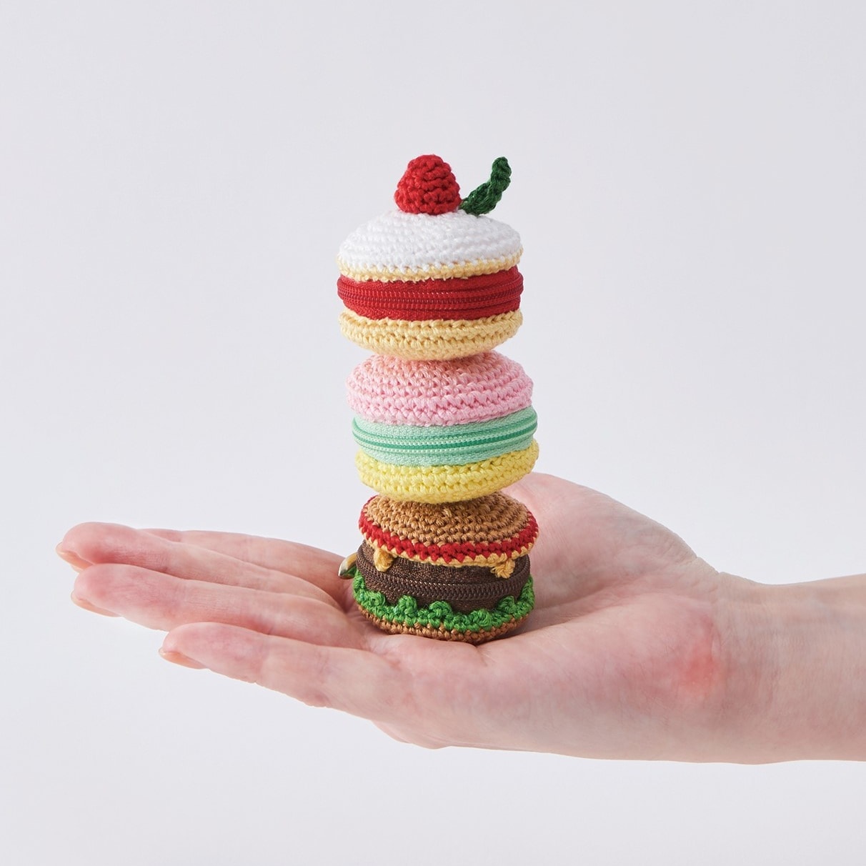 Cake, macaron, and hamburger pouches crocheted with COSMO embroidery floss, stacked on an open palm