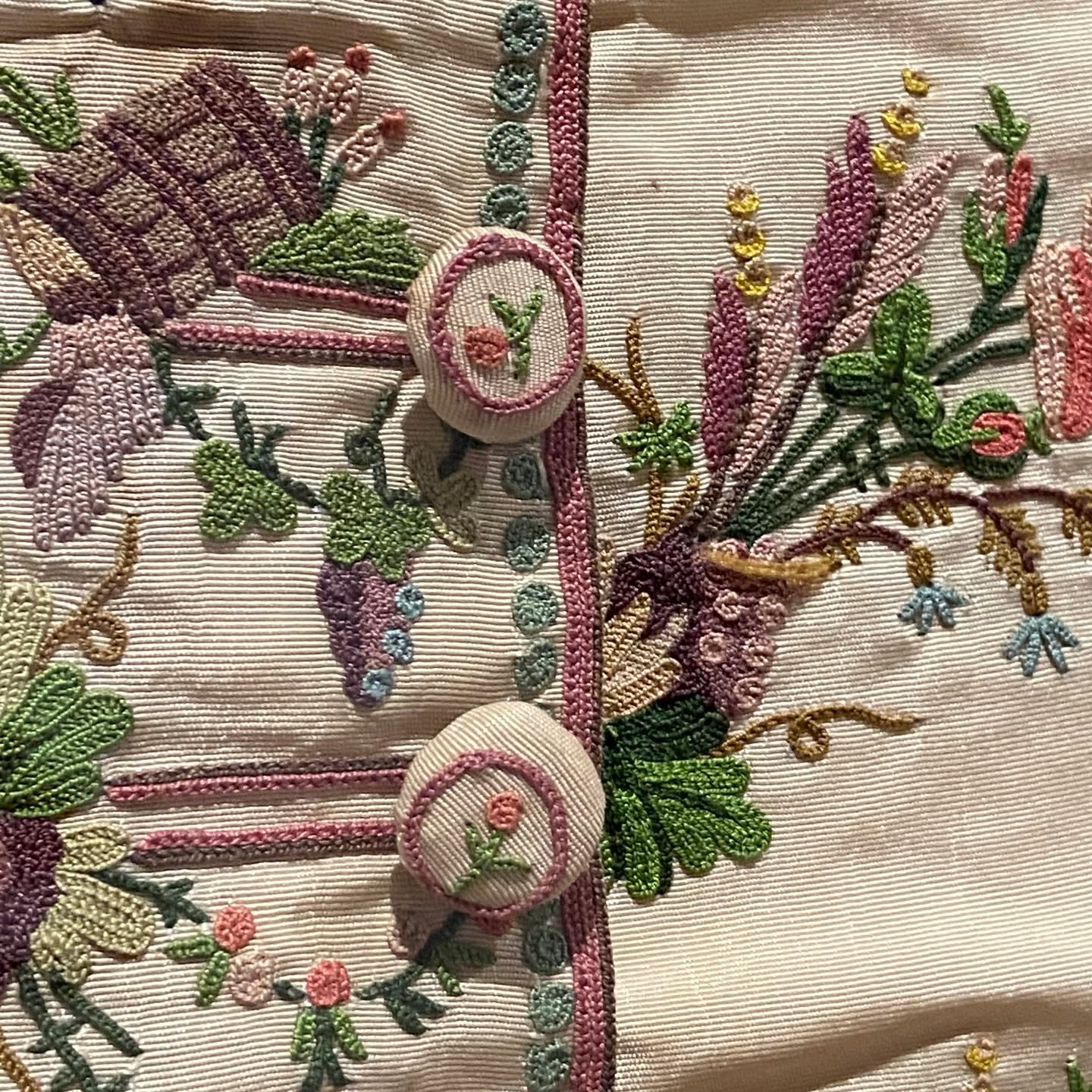 Cream ribbed silk with dense Rococo embroidery: grape clusters, rosebuds, lavender sprays, and rose-embroidered buttons