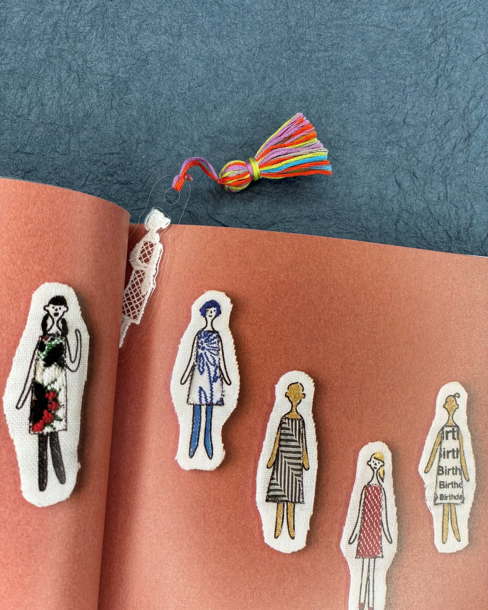 Handmade lace lady bookmarks with floss details on dark surface