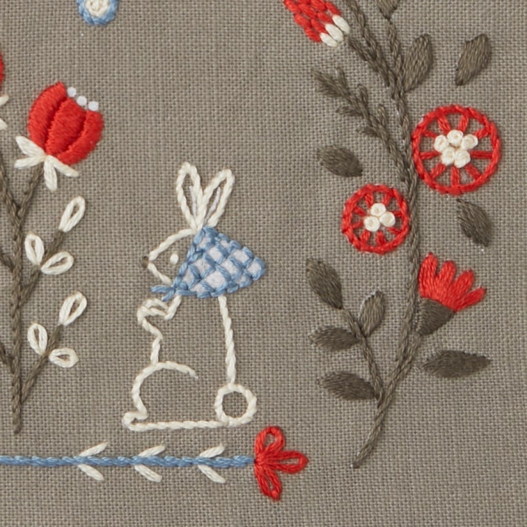 Close-up of white outline rabbit with checkered cape among red folk flowers