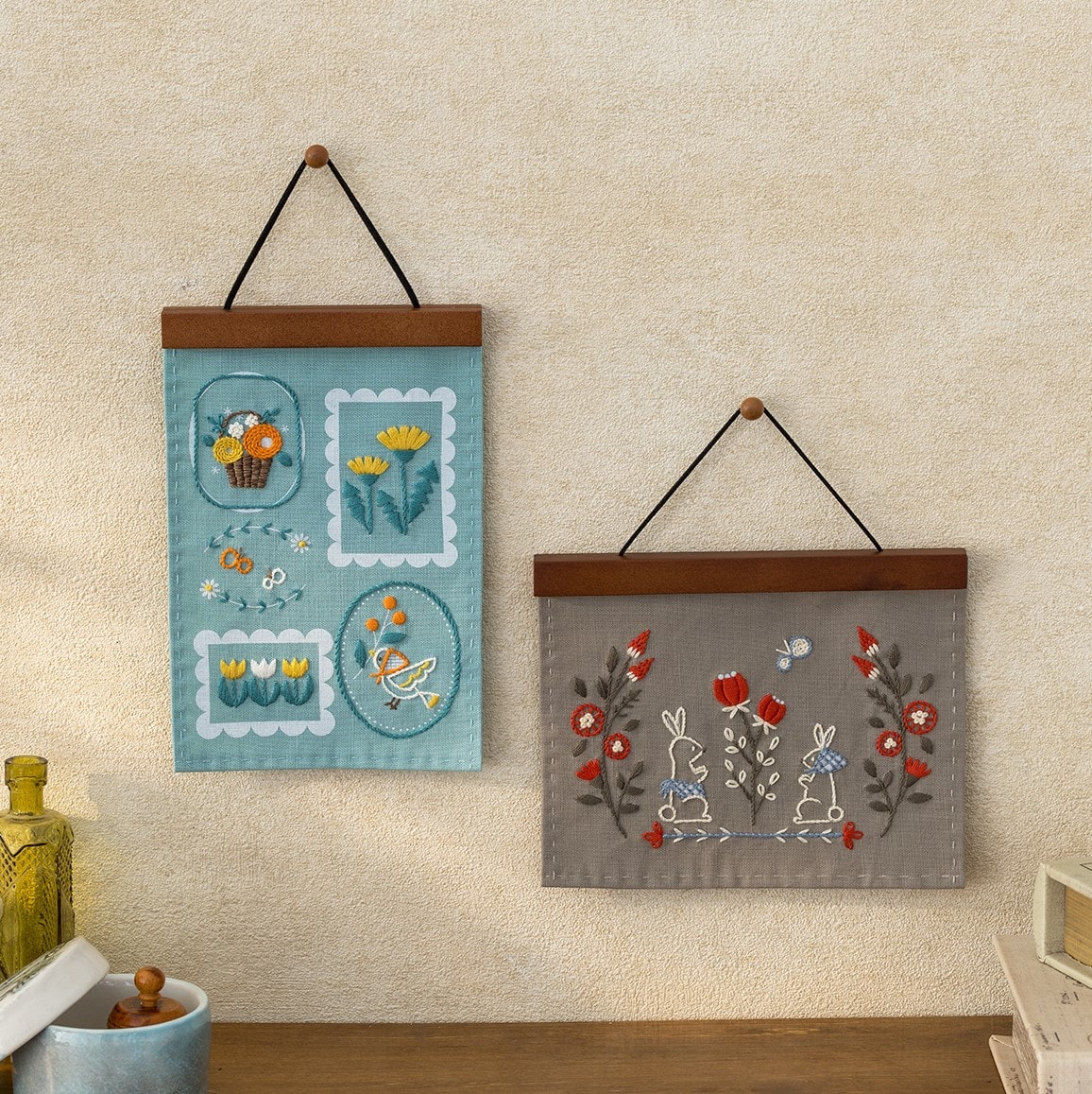 Teal stamp-frame hanging beside a gray rabbit folk hanging on the wall