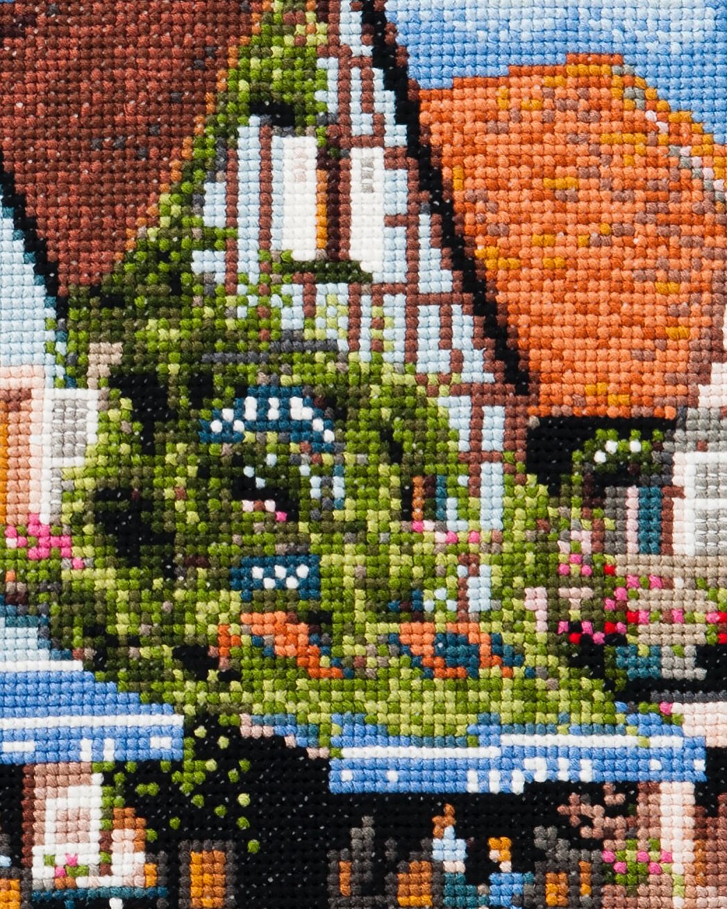 Close-up of the same café cross-stitch: greenery, terracotta roof, and awnings