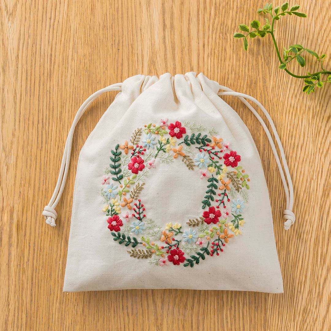 Cream drawstring pouch with multicolor circular floral wreath embroidery