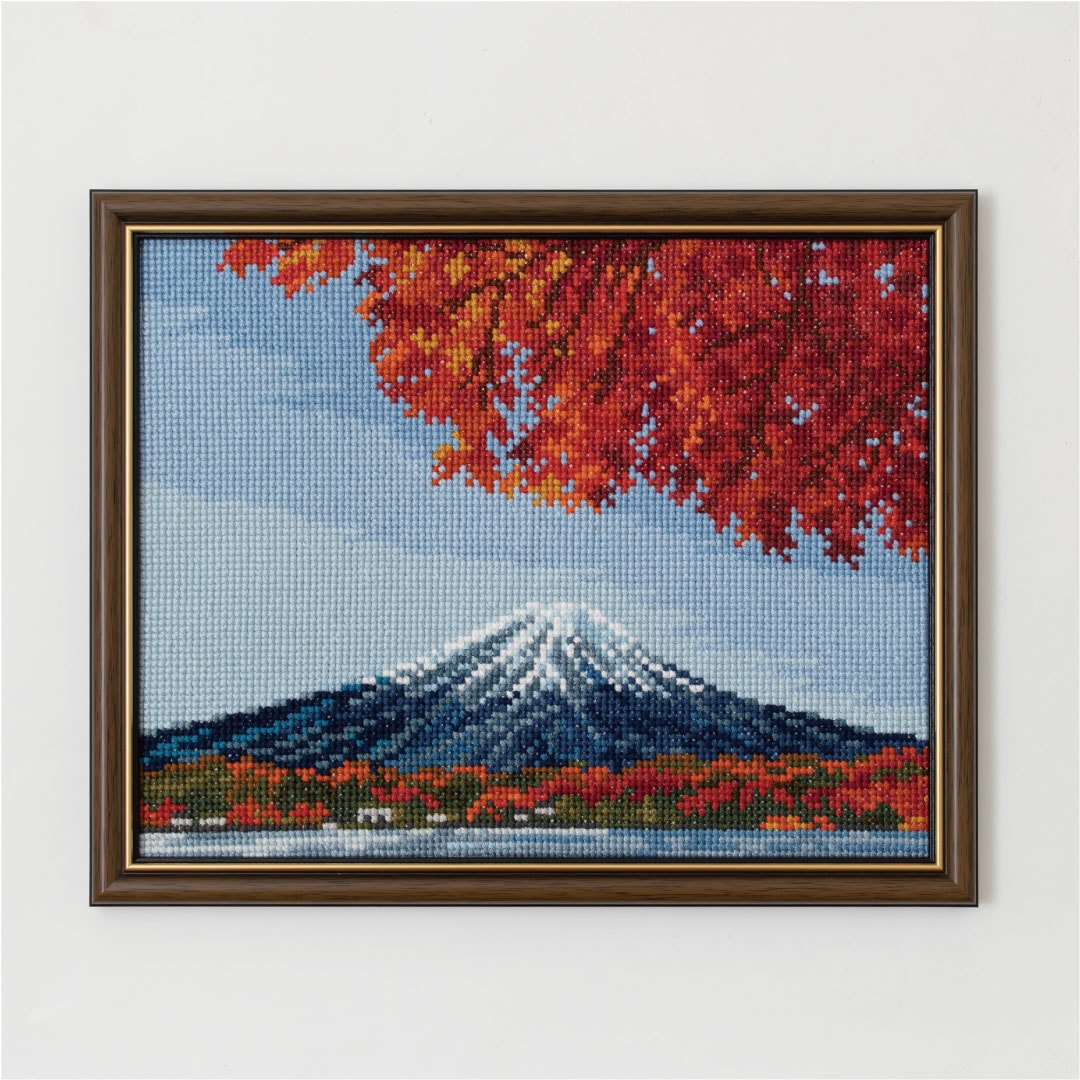 Framed cross-stitch of Mount Fuji with red maple leaves against a pale blue sky