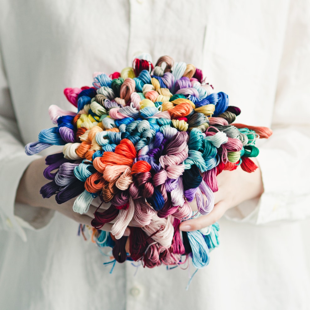 Hands holding a bouquet-like bundle of multicolor COSMO embroidery floss skeins