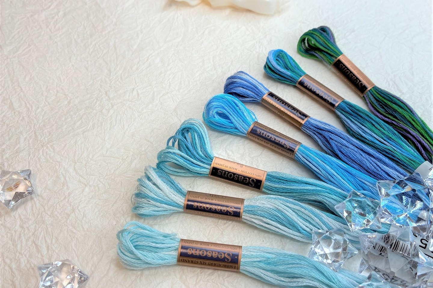 COSMO Seasons variegated floss skeins arranged with seashells and star-shaped beads