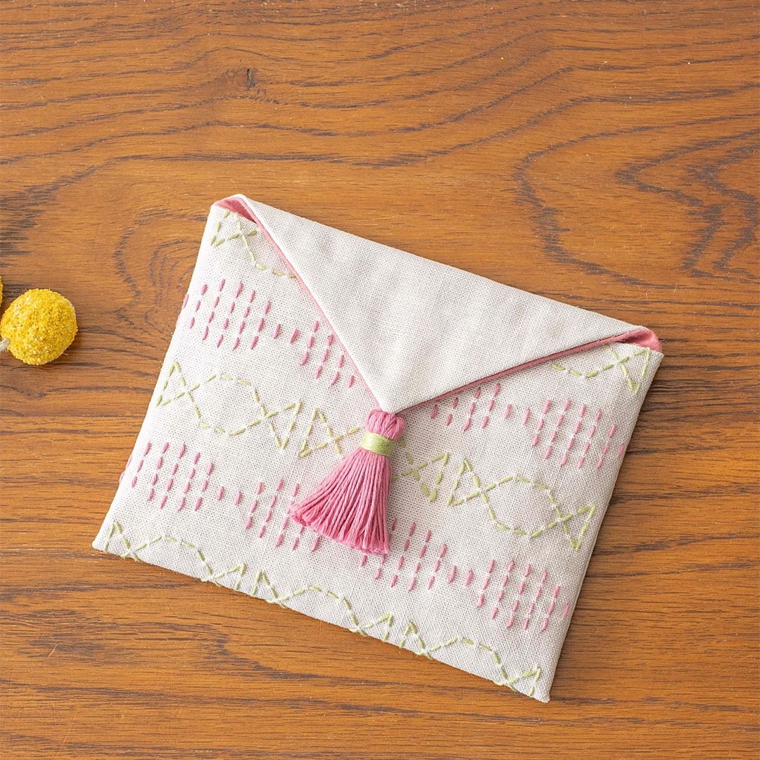 Pink and green sashiko-stitched fabric envelope pouch with tassel