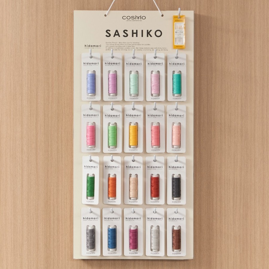 COSMO Hidamari sashiko thread display with needle pack hanging at top right