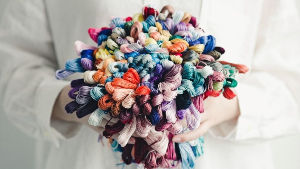 Hands holding a bouquet of multicolored COSMO embroidery floss skeins
