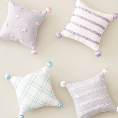 Six pastel pin cushions embroidered with Champagni metallic thread in various stitch patterns