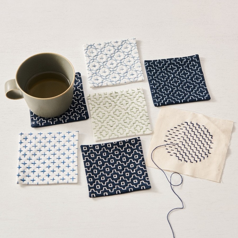 Sashiko coasters showing cross, interlocking, and wave geometric patterns in indigo and white