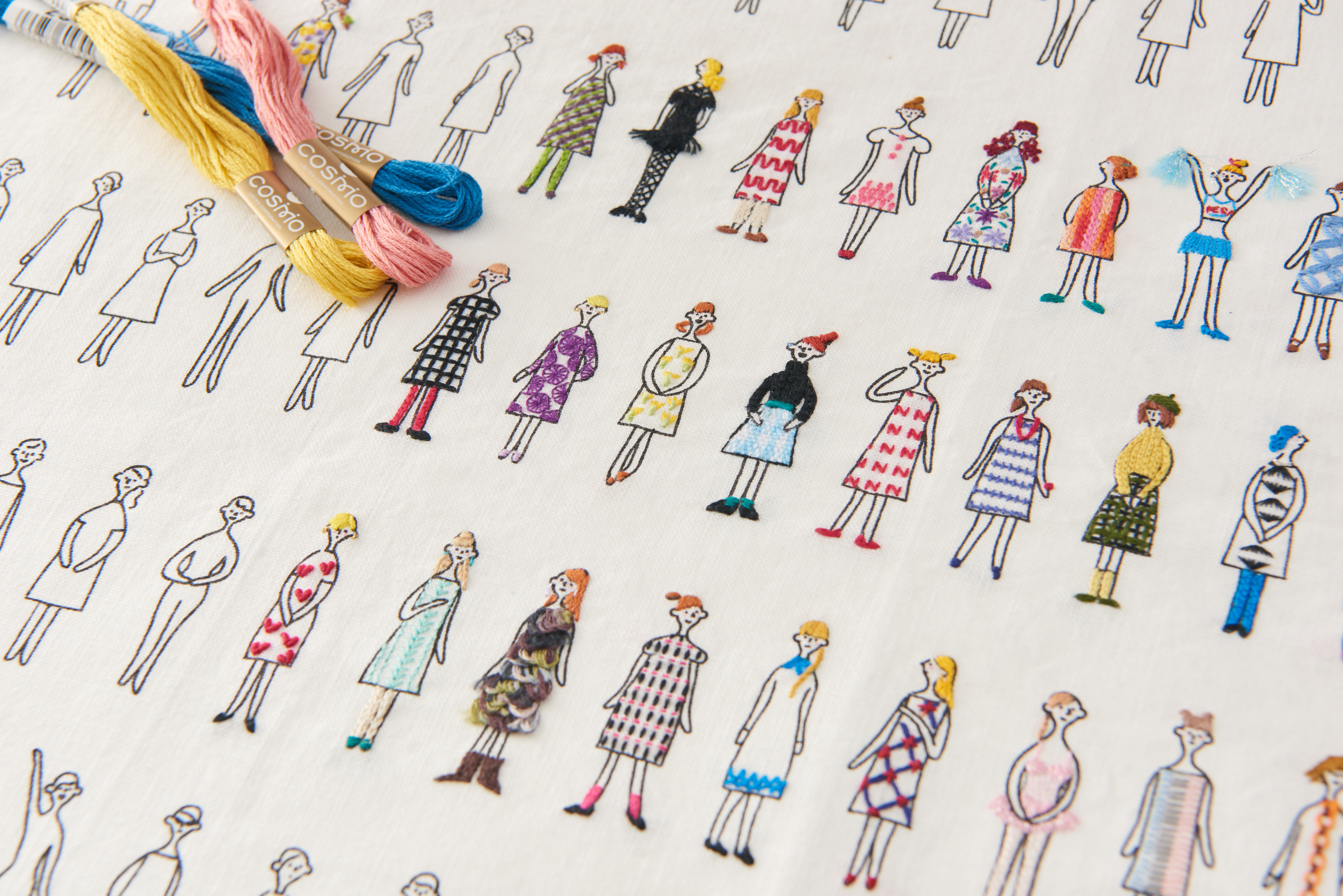 100 Ladies fabric with embroidered figures in colorful outfits, alongside COSMO embroidery floss skeins