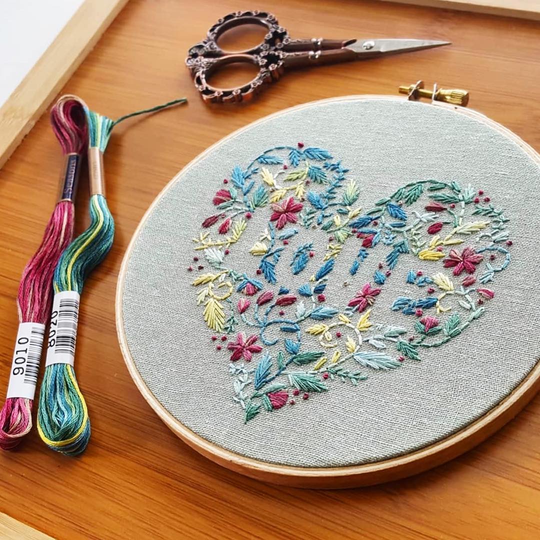 Floral heart embroidery hoop with COSMO Seasons floss skeins and ornate scissors on a wood tray