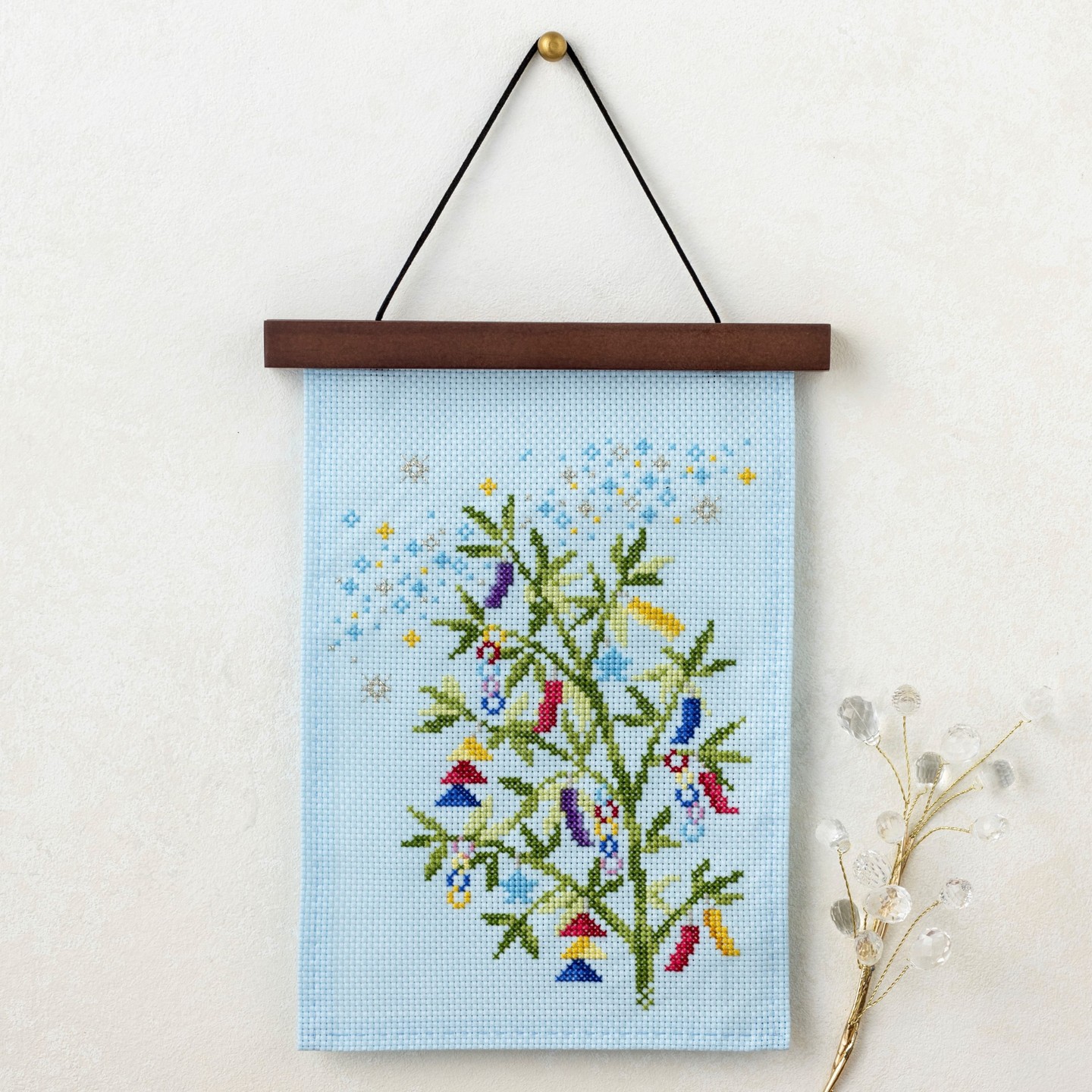 Cross-stitch Tanabata hanging with bamboo, colorful tanzaku wish strips, and stars on blue cloth