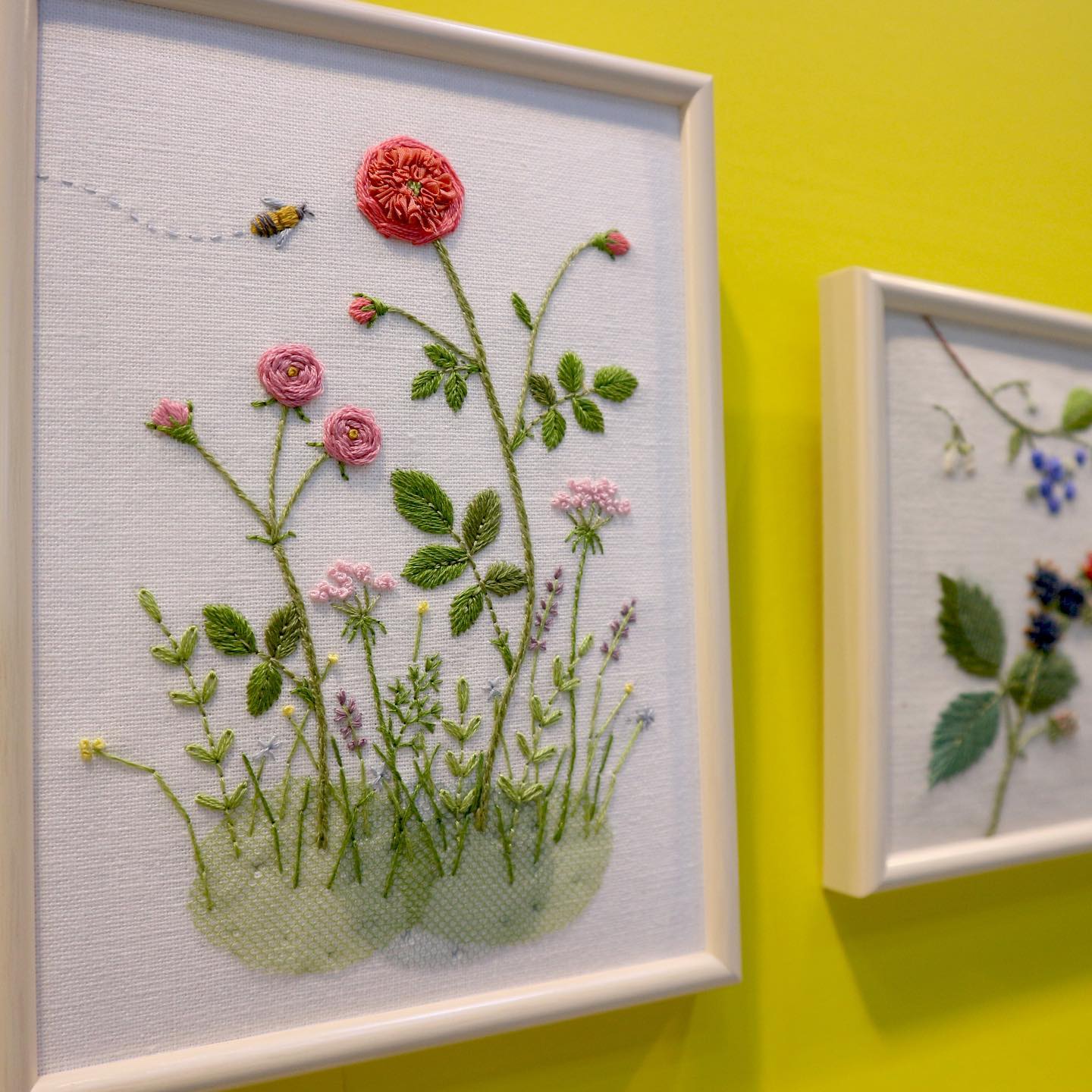 Raised botanical rose and bee embroidery on a yellow wall