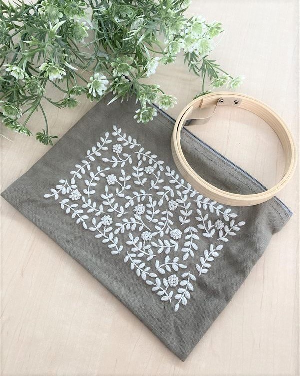 Gray zip pouch with dense white botanical vine embroidery and empty hoop prop