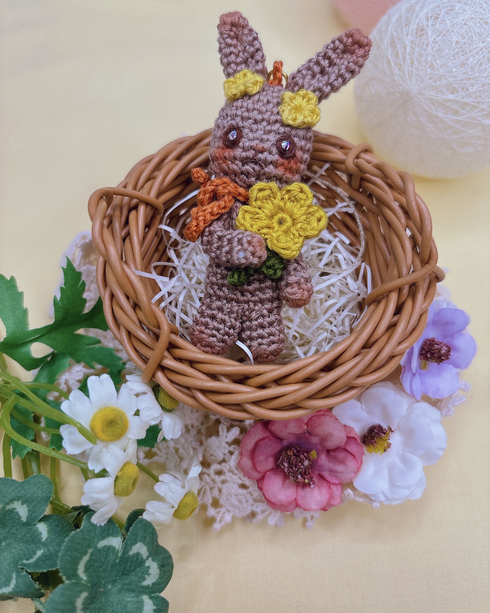 Small crocheted bunny in a woven nest with flowers, made with fine COSMO thread