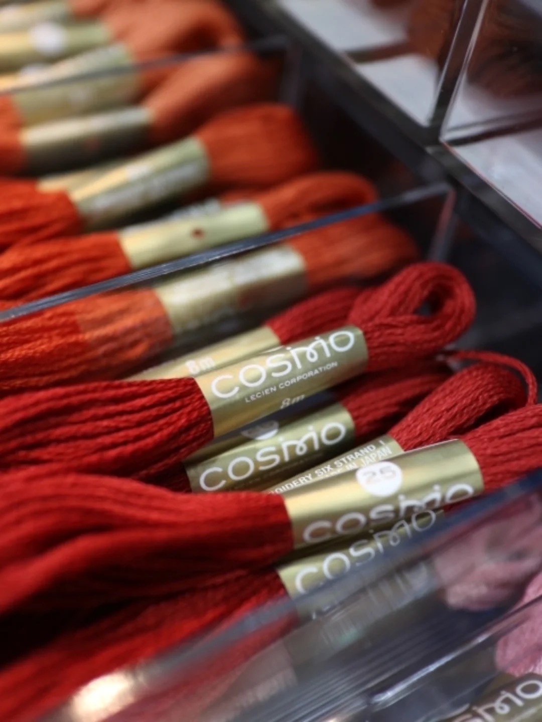 COSMO embroidery floss in a clear retail rack showing red and orange shades